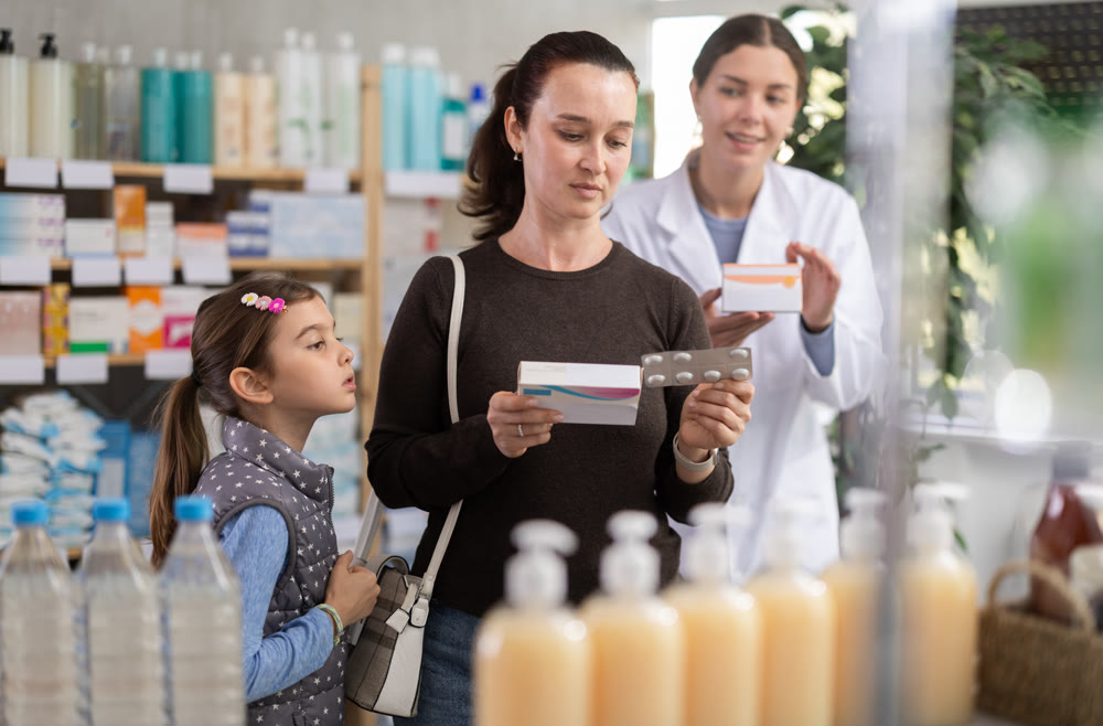 woman with a child buys medicines at a pharmacy with a pharmacist