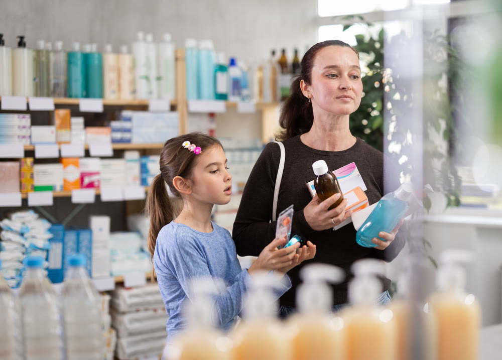 Woman with small daughter customers in drugstore buy different products