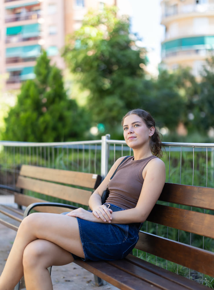 Young woman relaxing on wooden park bench