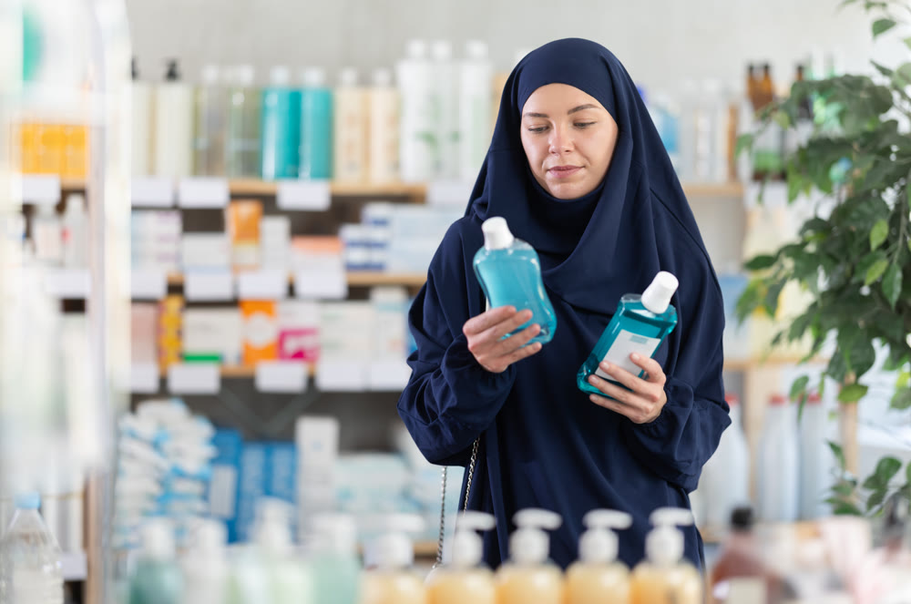 Young woman in hijab chooses mouthwash at pharmacy