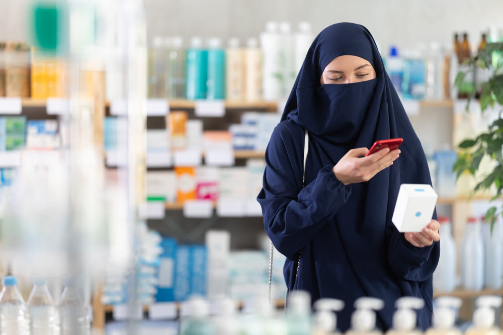 Young Muslim woman customer scanning QR-code on pills box