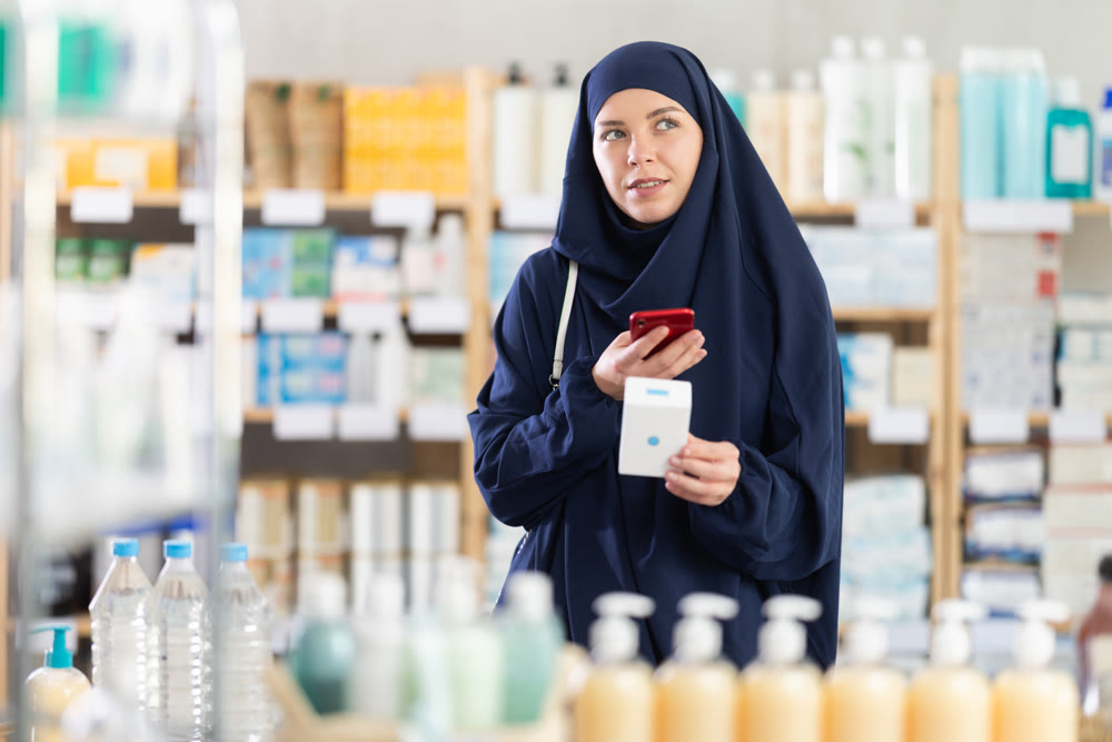 Young Muslim woman customer scanning QR-code on pills box
