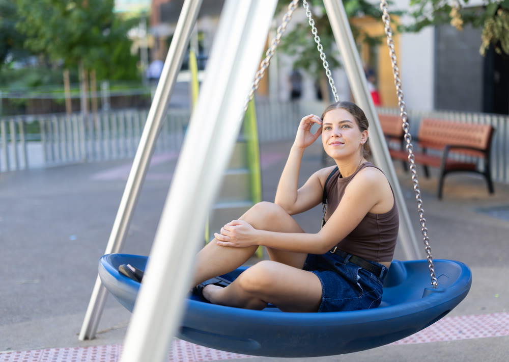 Girl is relaxing on swing in park, spending time alone.