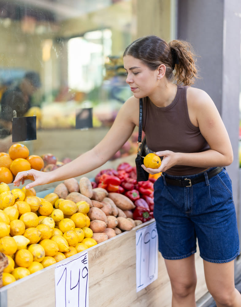 Girl is walking around street market or fair, choosing lemon goods