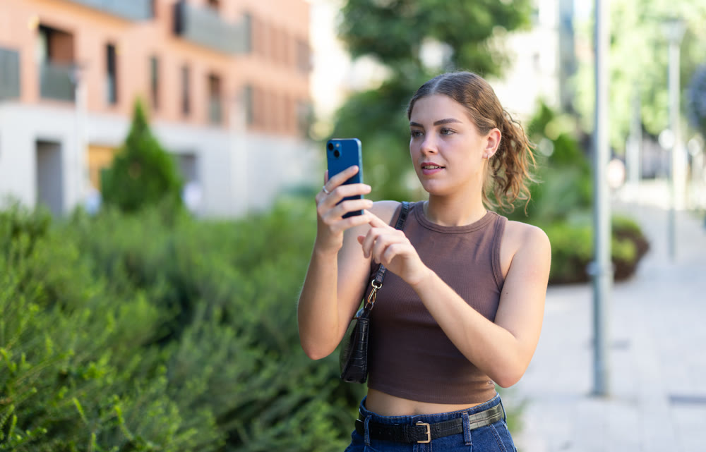 Girl walks around city district with mobile phone