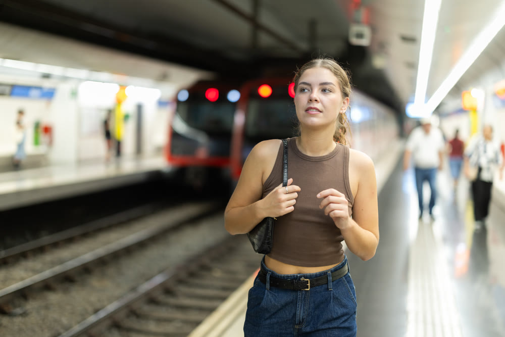 Young woman standing on metro station platform waiting for train