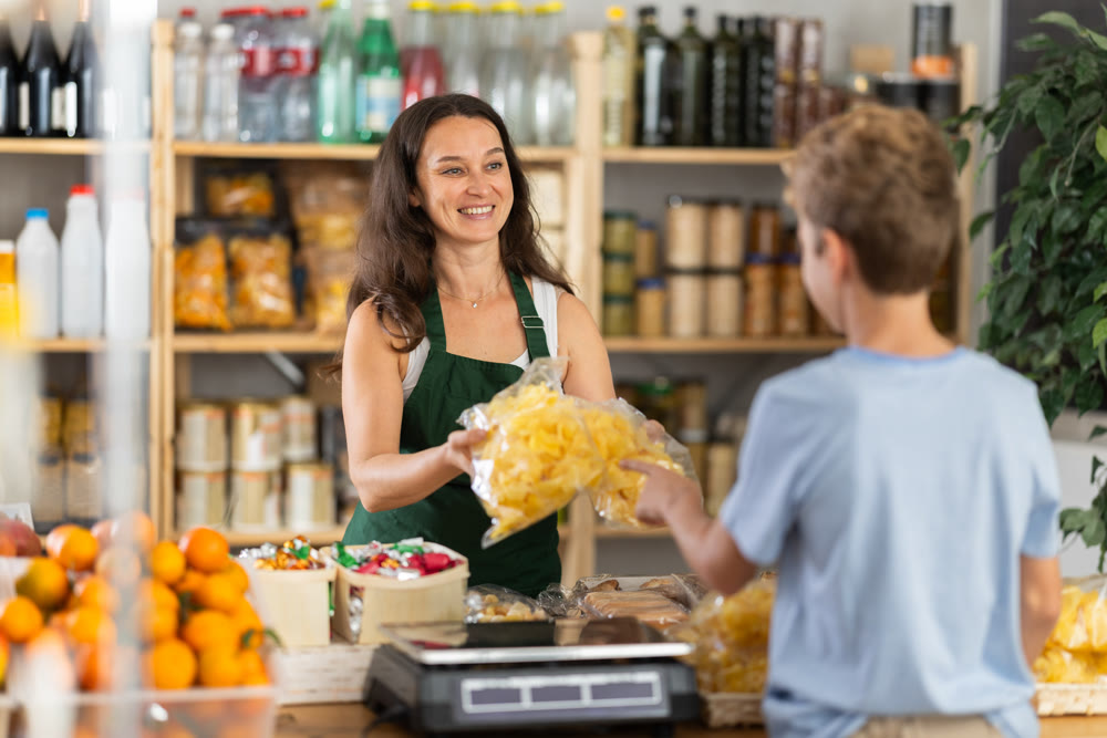 Positive female vendor offers a boy a choice of different chips