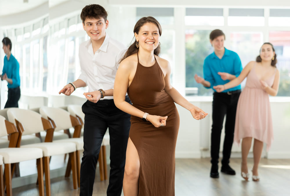 Couple in evening dresses enjoys pair dance boogie-woogie, interacting with each other on floor