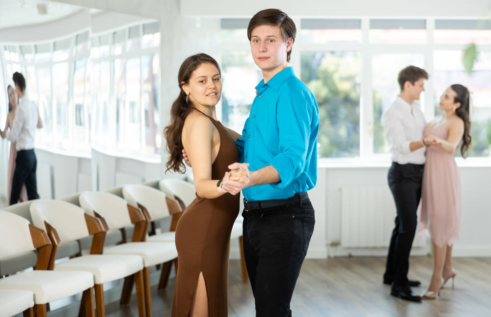 Couple in evening dresses enjoys pair dance tango, interacting with each other on floor