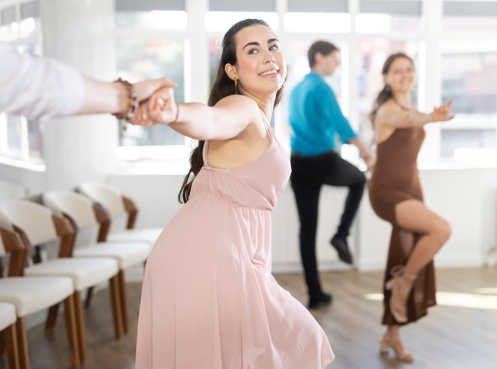 Dance studio where young couples in festive clothes learn to dance swing