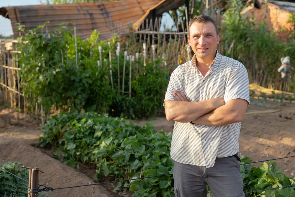 Smiling adult man amateur gardener posing in backyard vegetable garden
