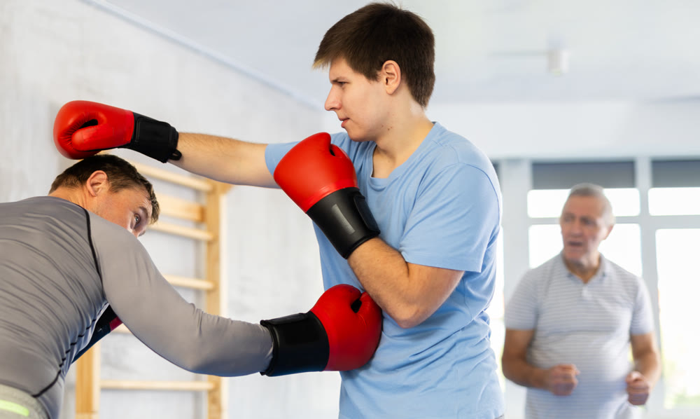 Guy getting hit to torso from sparring partner at boxing training