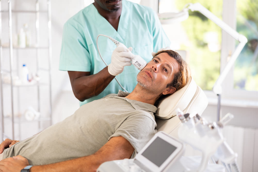 Adult male patient receiving facial procedure using cooling attachment