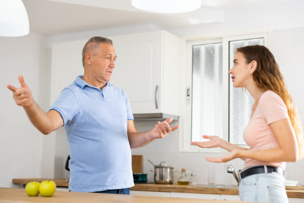 Adult daughter arguing with her mature father in the kitchen