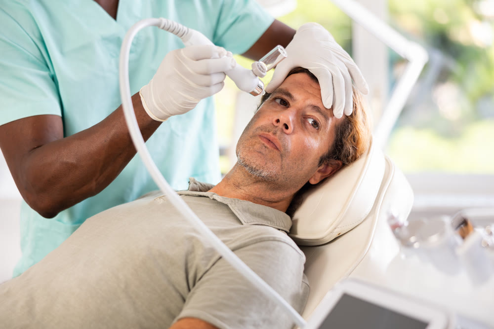 Adult man undergoing facial procedure with application of atomized nutrients