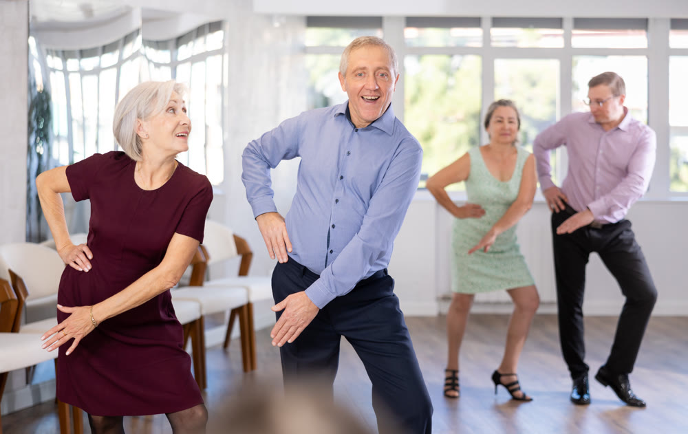 Mature positive people dancing twist together at dance studio