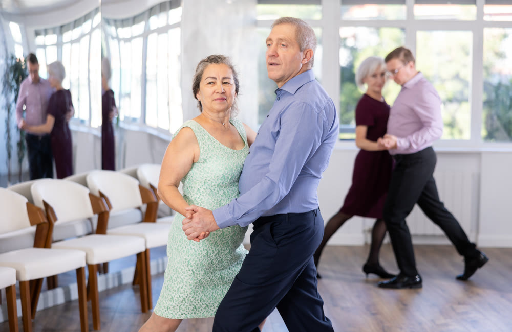 Senior man and elderly woman are dancing classic version of waltz in couple
