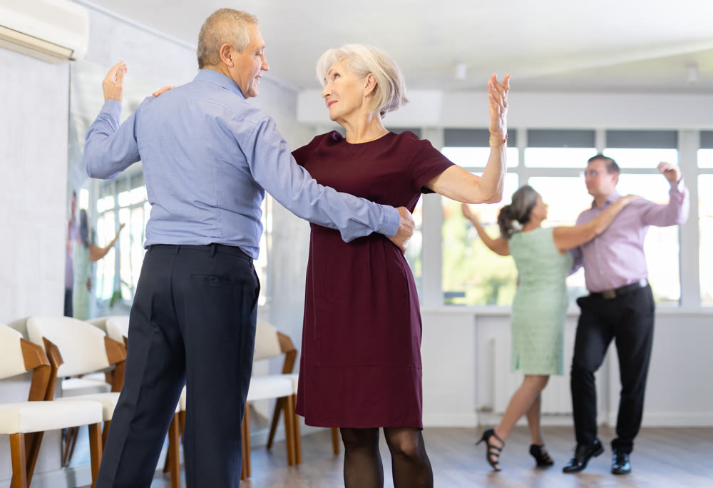Senior man and elderly woman are dancing classic version of waltz in couple
