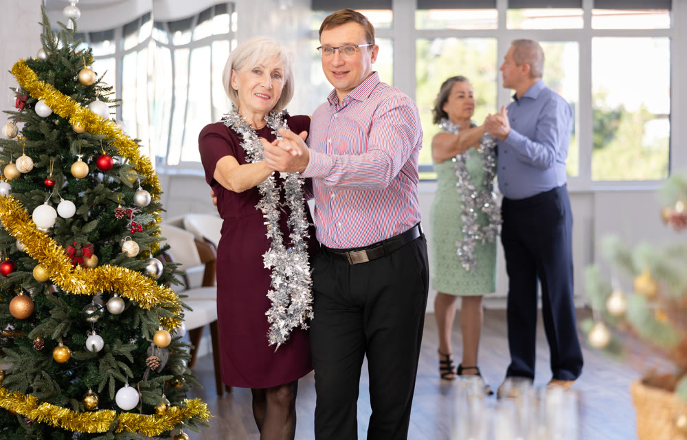 Middle-aged man and elderly woman dancing contemporary discofox in couple in New Year atmosphere