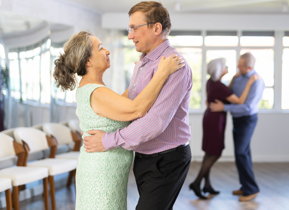 Smiling couple looking at each other while dancing slow dance in ballroom