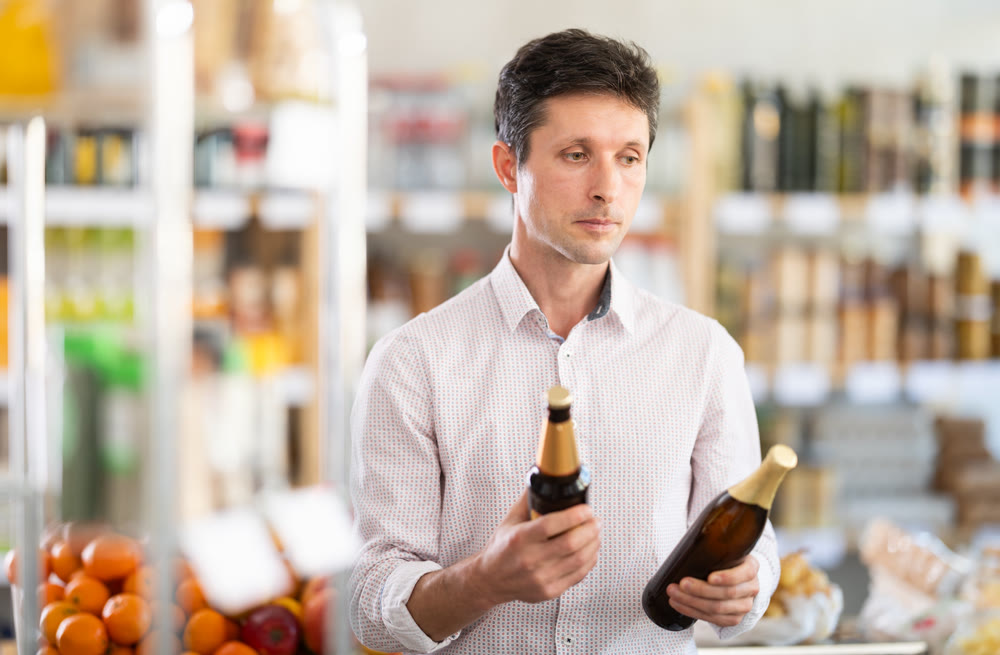 Man in light shirt choose and buy beer in store