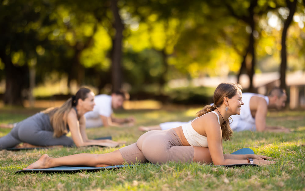 Girl performing Half Pigeon Pose during group yoga in park