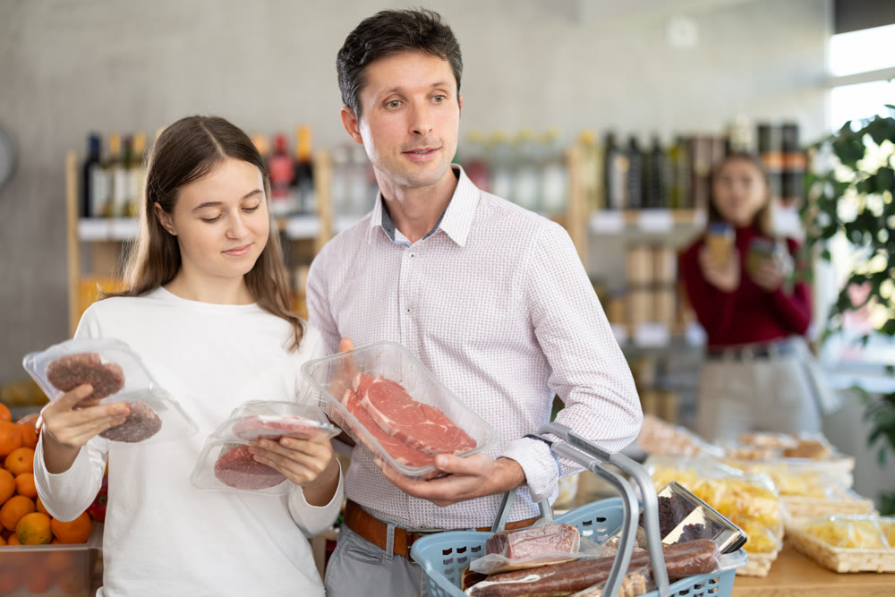 Man and his teenage daughter choosing hamburger or beef entrecote in grocery