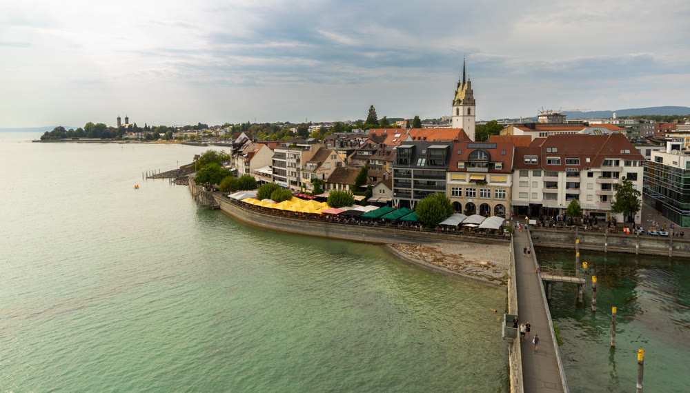 Scenic shoreline featuring harbor pier and church tower along Lake Constance