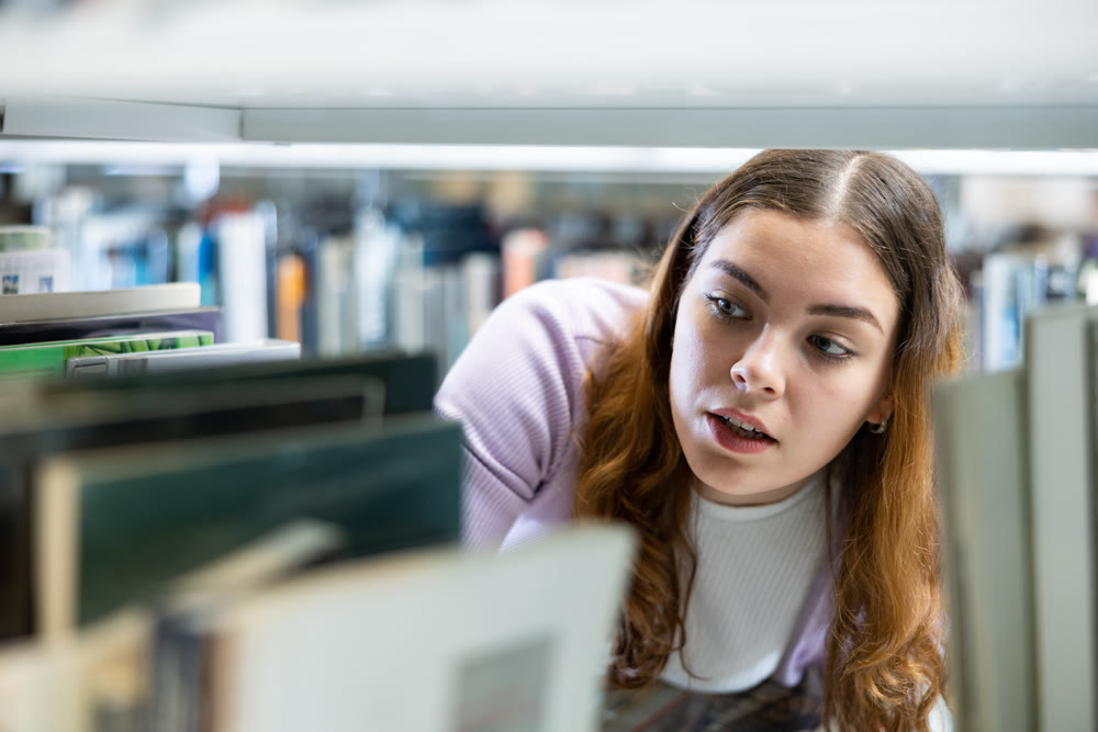 Woman looking for the right book on the bookshelf in public library