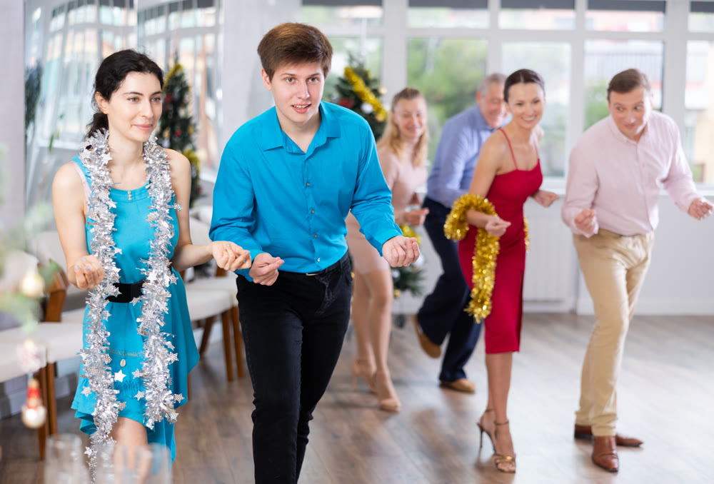 Cheerful young couple dancing Lindy Hop at Christmas celebration in office