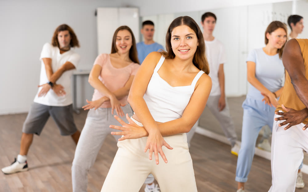 Happy multiracial men women of different ages performing dynamic energetic dancing movements in modern loft studio