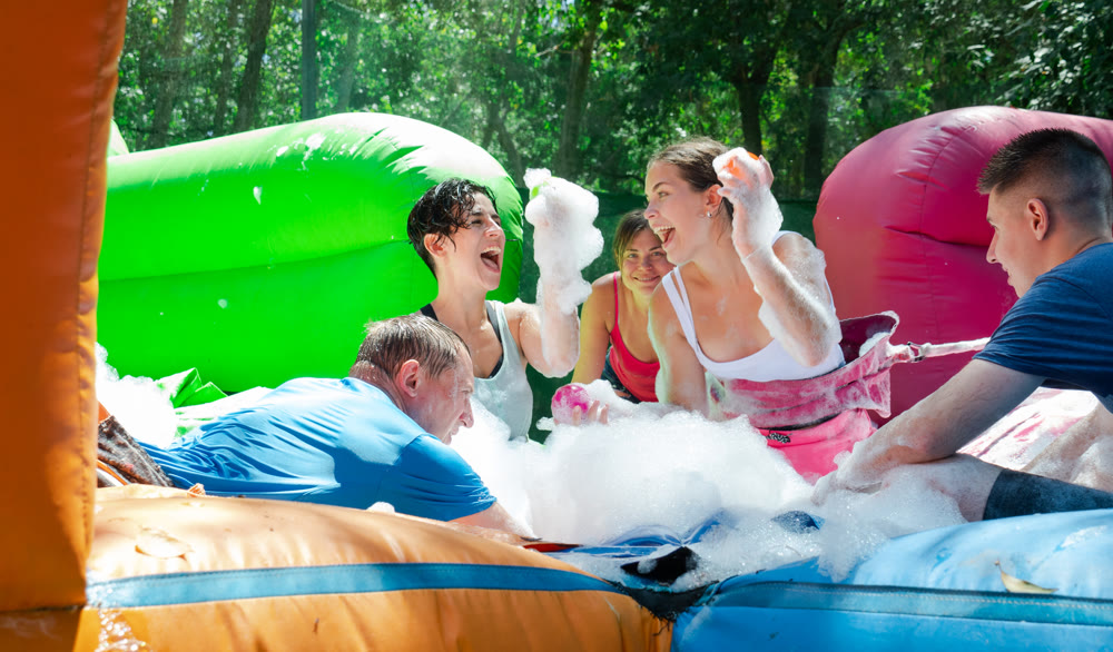 Cheerful men and women playing in foam pool in amusement park