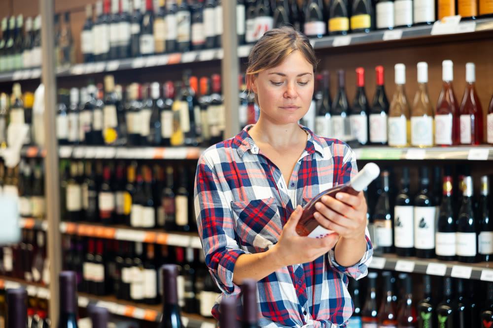 Woman choosing wine in supermarket