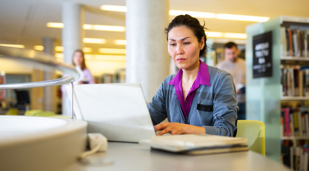 Portrait of positive woman with laptop in public library