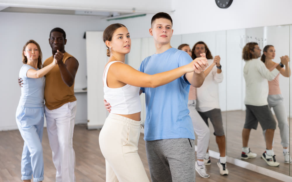 Man and woman in pairs learning to dance waltz in studio