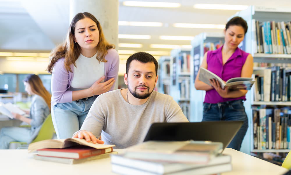 Man working with female colleague on joint project in library