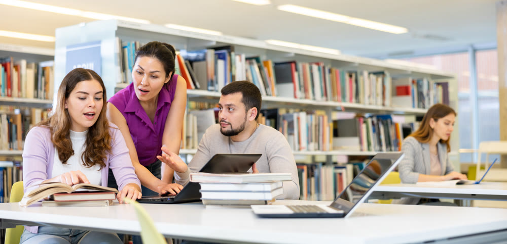 Group of friendly students working on joint research in library