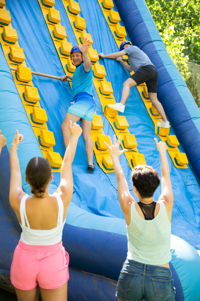 Happy active man climbing on inflatable castle with wooden sticks
