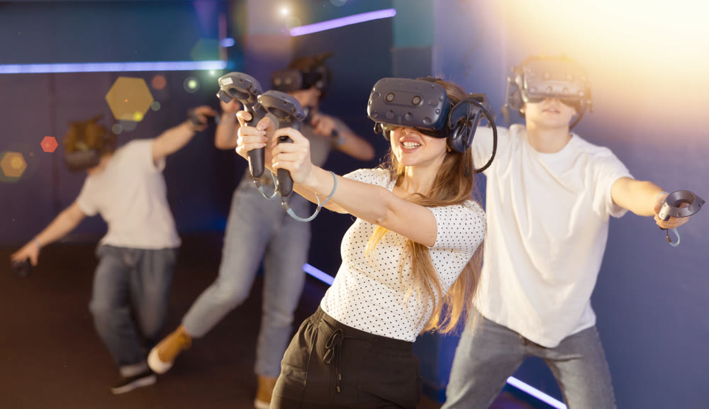 Portrait of woman using virtual reality goggles controlling joysticks standing in dark room
