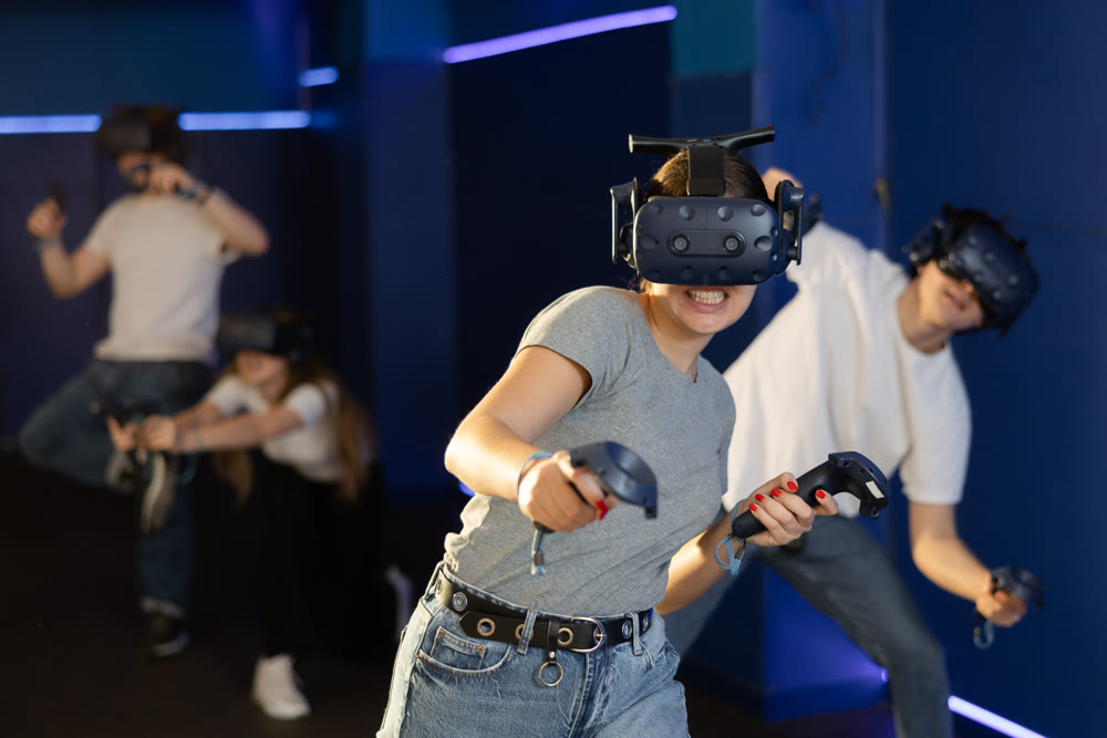 Excited young woman in VR goggles having fun in virtual reality room