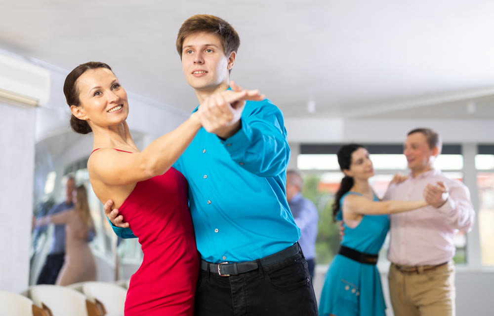Woman paired with male partner dance samba in dance class with students