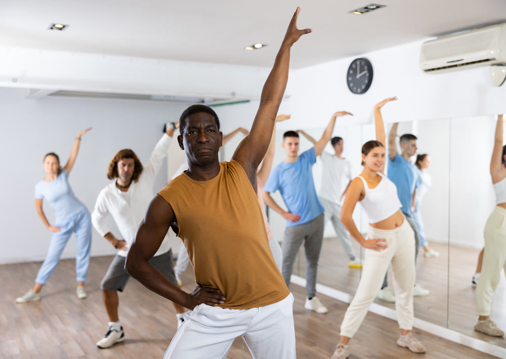 African american man practicing active dance moves during rehearsal with group in dancing studio.