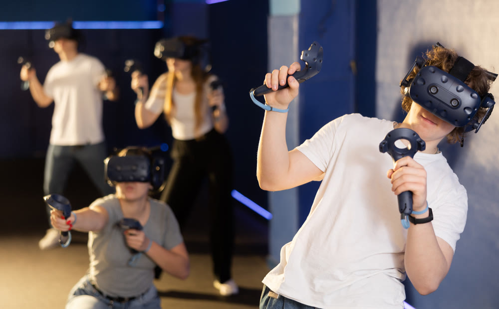 Guy with handheld controllers and VR glasses playing virtual game