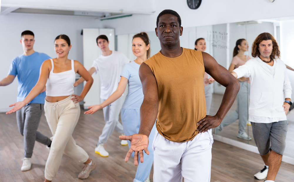 Group of different people rehearsing dance in dance studio