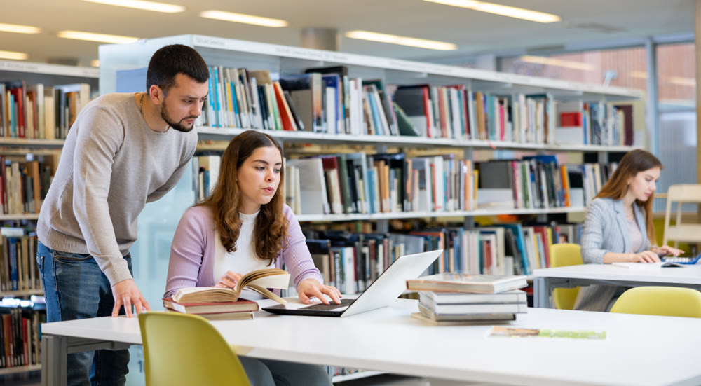 Man working with female colleague on joint project in library