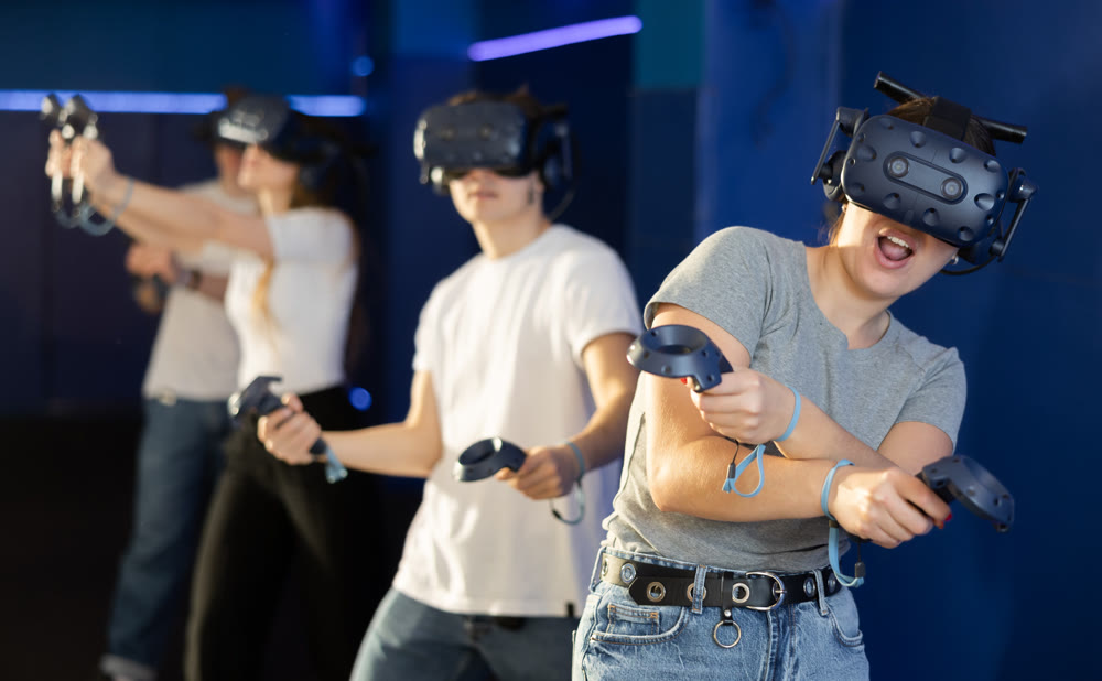 Young woman in VR glasses playing virtual game with handheld controllers