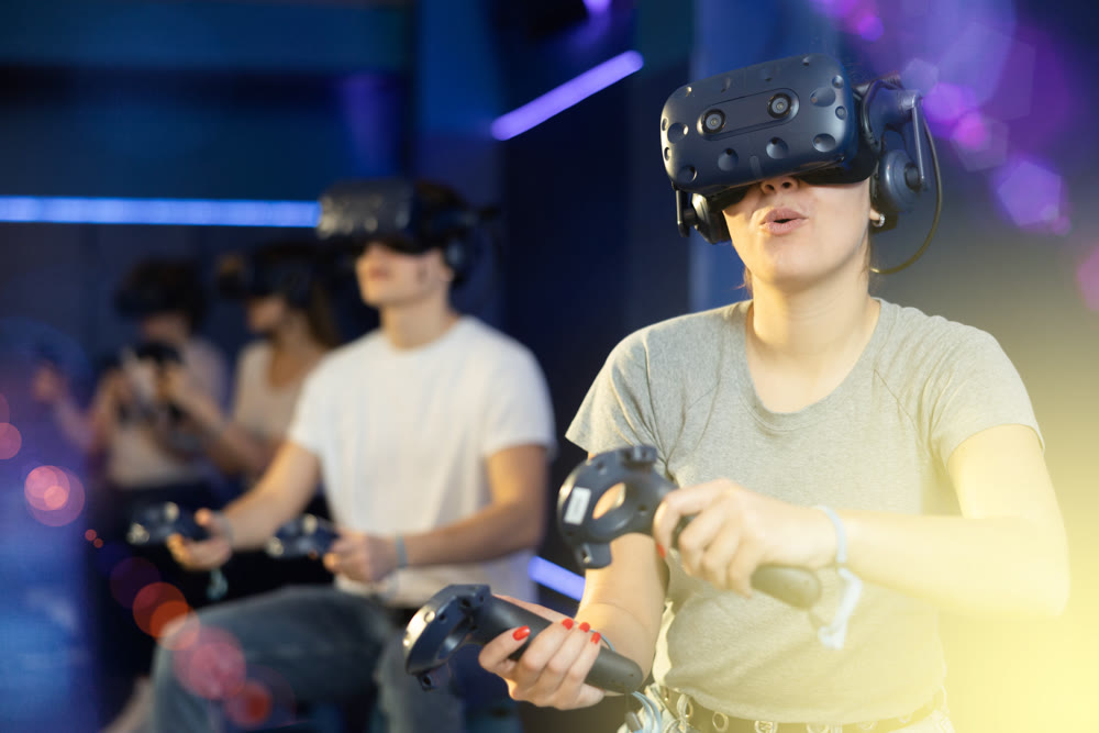 Girl is enjoying exciting movie with friends in VR glasses in room