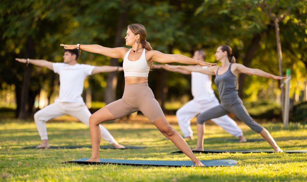 Yoga lesson visitors perform virabhadrasana in park