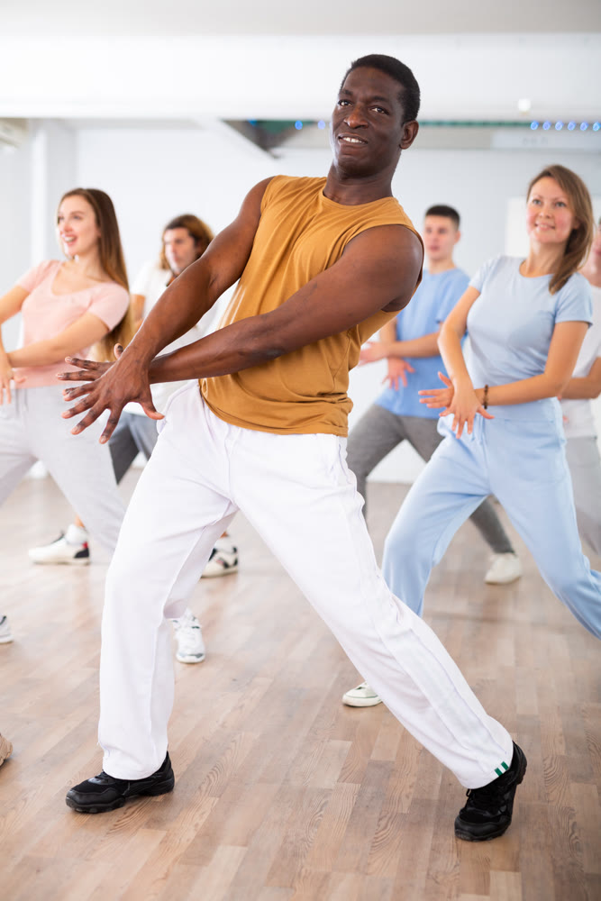 Group of different people rehearsing dance in dance studio