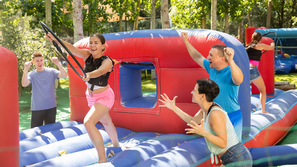 Happy young woman competing with friends in collect hoops on inflatable arena